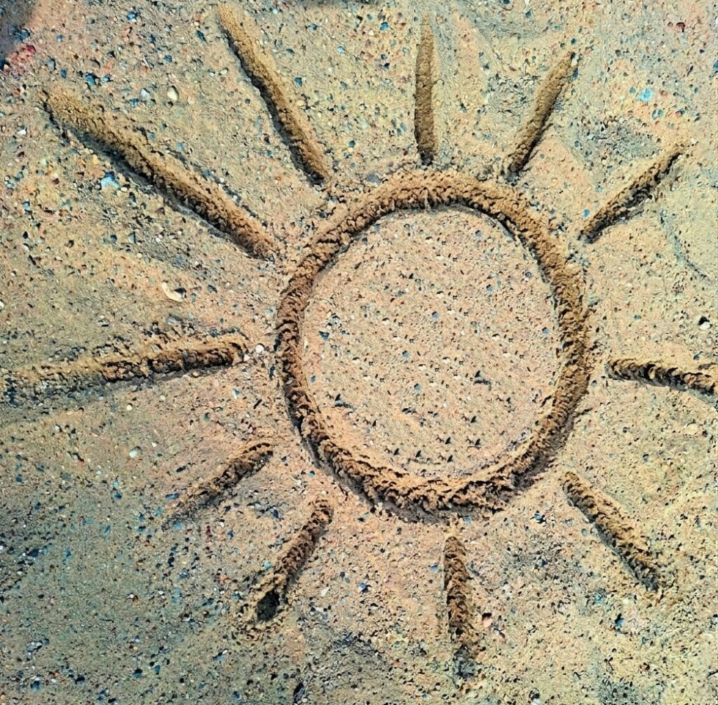 Eine gemalte Sonne im Sand