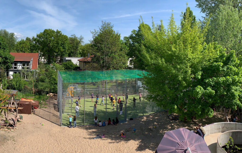 Ballspielplatz mit vielen Kindern und Zuschauern